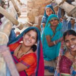 Jaipur Rugs women artisans smiling while they work on the loom.